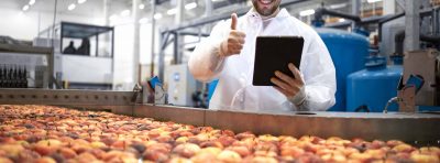 Technologist showing thumbs up in food processing factory and checking quality of apple fruit.